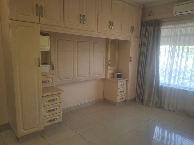 A bedroom featuring extensive built-in cabinetry, tiled flooring, and an integrated air conditioning unit, offering ample storage space.