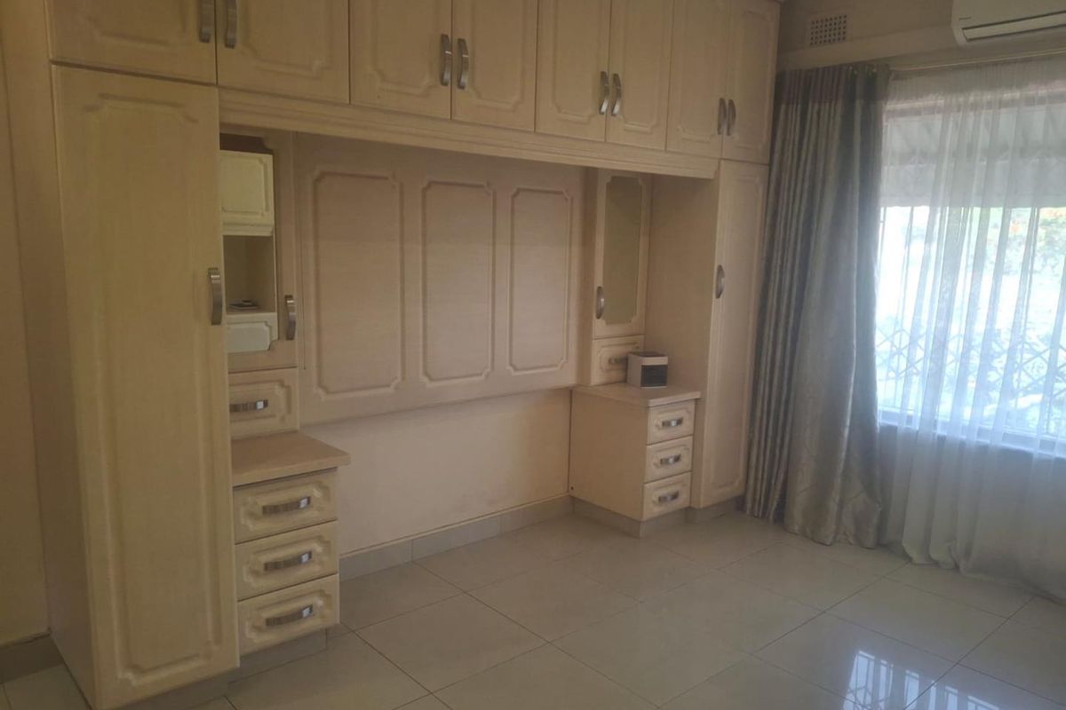 A bedroom featuring extensive built-in cabinetry, tiled flooring, and an integrated air conditioning unit, offering ample storage space.
