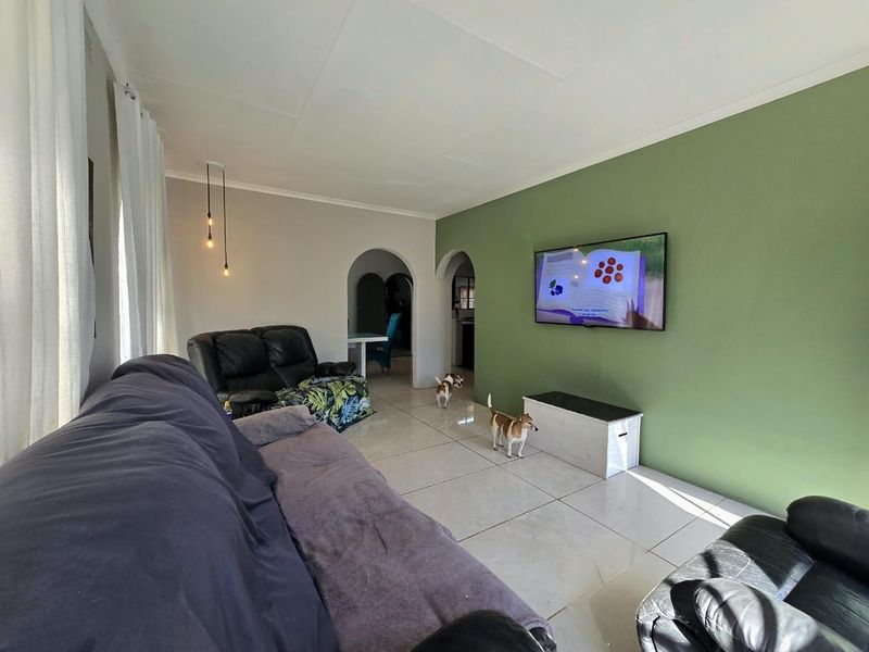 A living room featuring tiled flooring, coved ceilings, and distinctive archways leading to adjacent spaces, finished with a green accent wall.