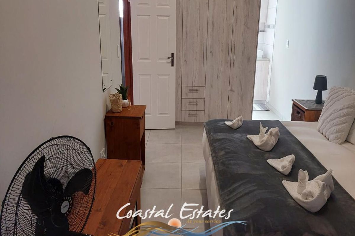 A well-maintained bedroom featuring built-in wooden cabinetry, tiled flooring, and an en-suite bathroom visible through the doorway.