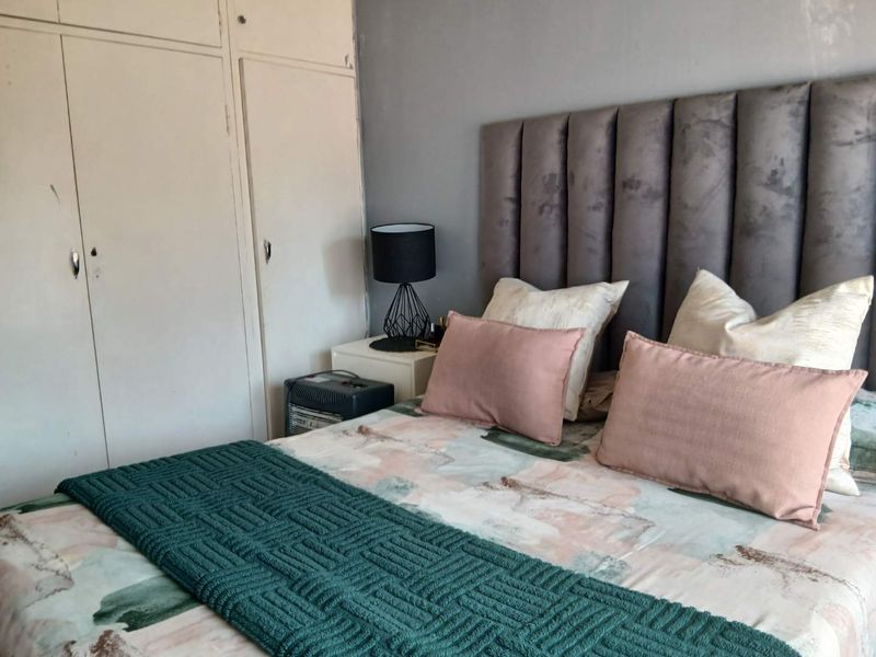 A bedroom featuring built-in cupboards and a neutral wall finish, offering a functional space with potential for cosmetic updates.