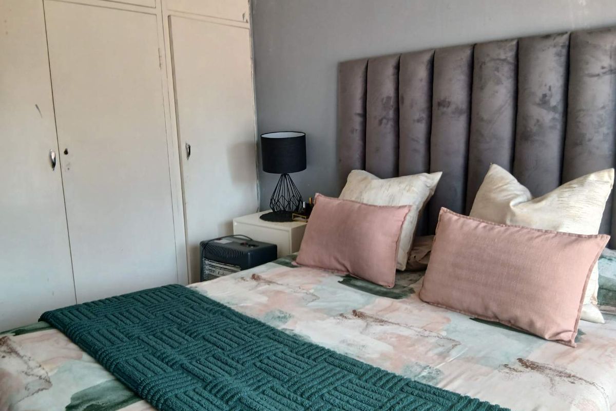 A bedroom featuring built-in cupboards and a neutral wall finish, offering a functional space with potential for cosmetic updates.