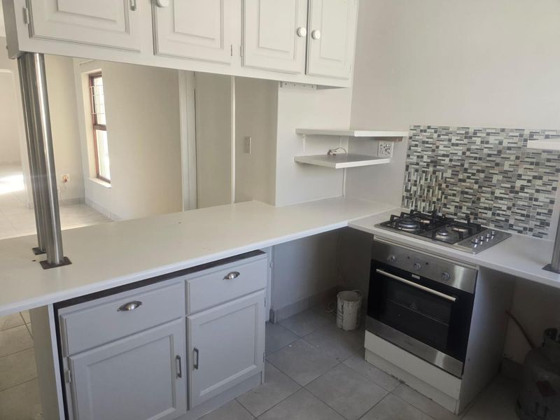 A functional kitchen featuring built-in cabinetry, a gas hob, an integrated oven, and a mosaic tile backsplash with neutral ceramic floor tiles.