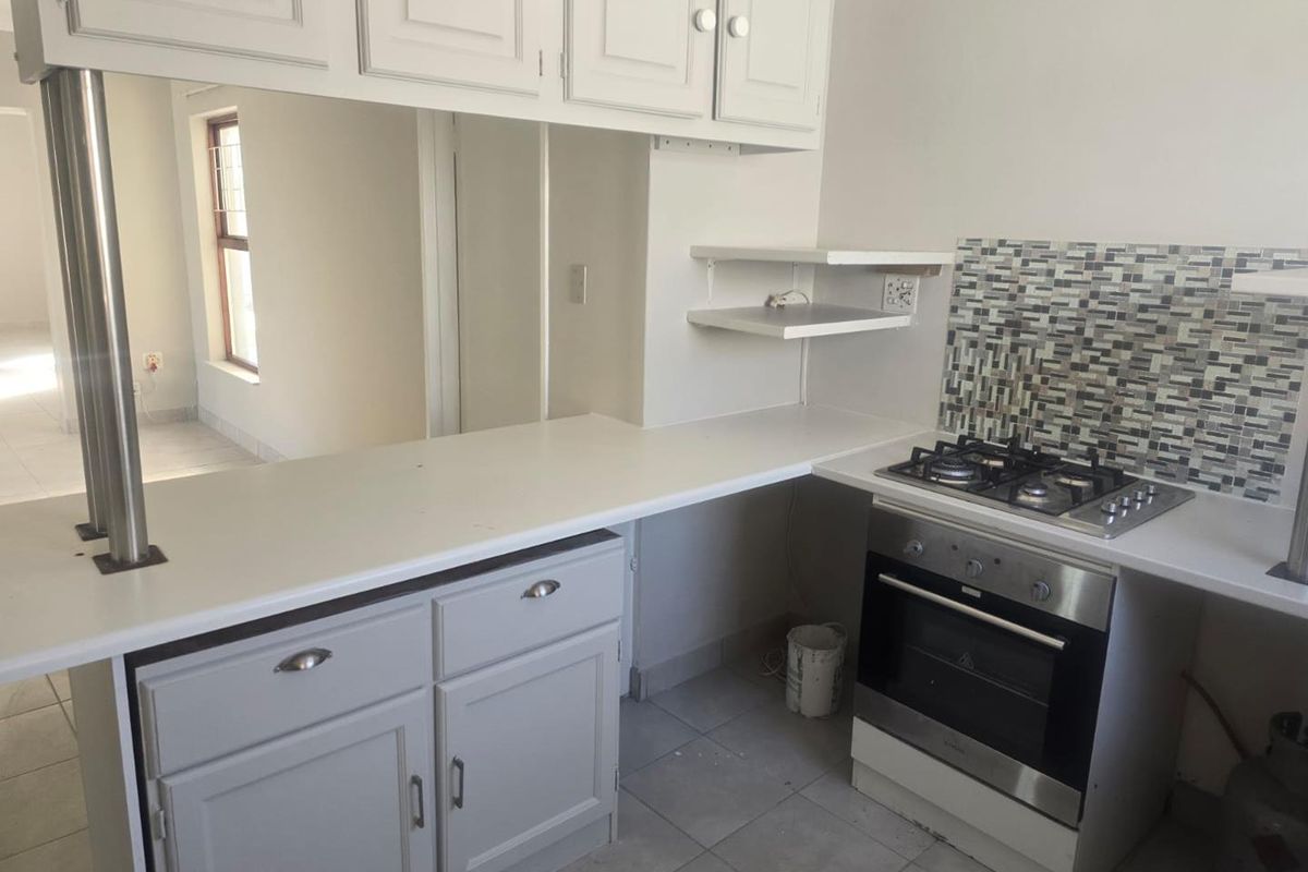 A functional kitchen featuring built-in cabinetry, a gas hob, an integrated oven, and a mosaic tile backsplash with neutral ceramic floor tiles.
