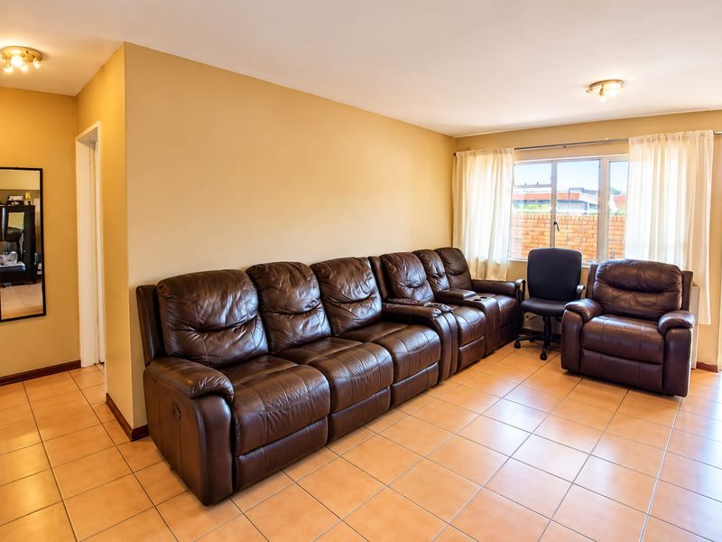 Spacious living room featuring ceramic tile flooring, neutral wall tones, and a sliding glass door providing access to the exterior.