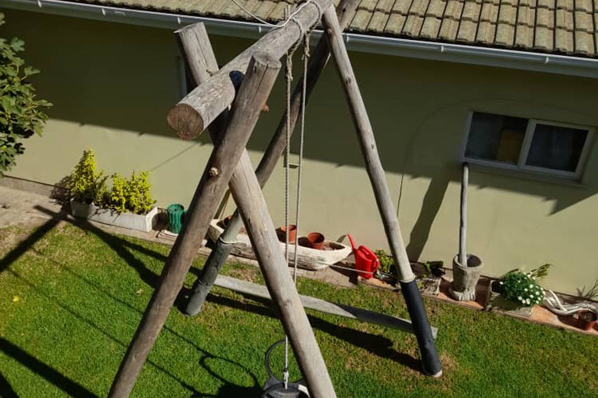 An elevated view of a rear garden area featuring a lawn and a wooden swing set structure against the back wall of the house.