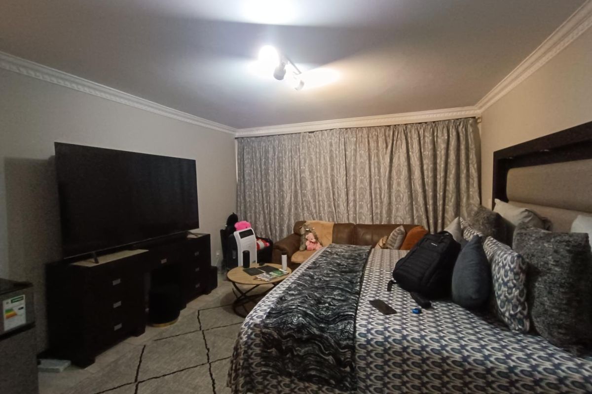 A spacious bedroom featuring crown molding and neutral wall finishes, providing a comfortable and functional sleeping area.
