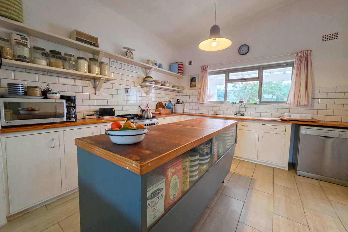 A functional kitchen featuring a central island, timber countertops, subway tile backsplash, and ample built-in cabinetry with integrated appliances.