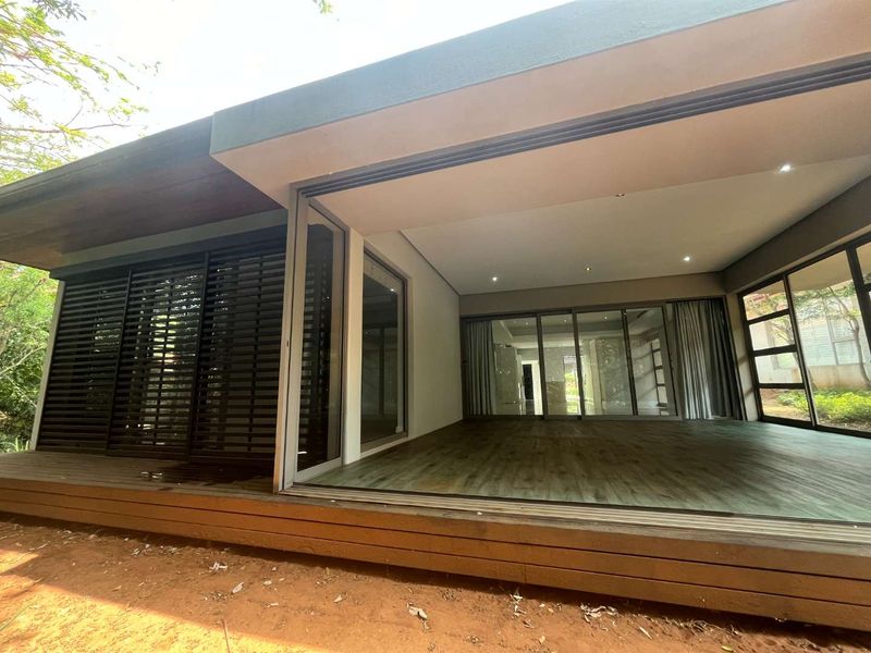 Spacious covered patio featuring timber decking, large sliding glass doors, and integrated recessed lighting, offering a seamless transition to the outdoor area.
