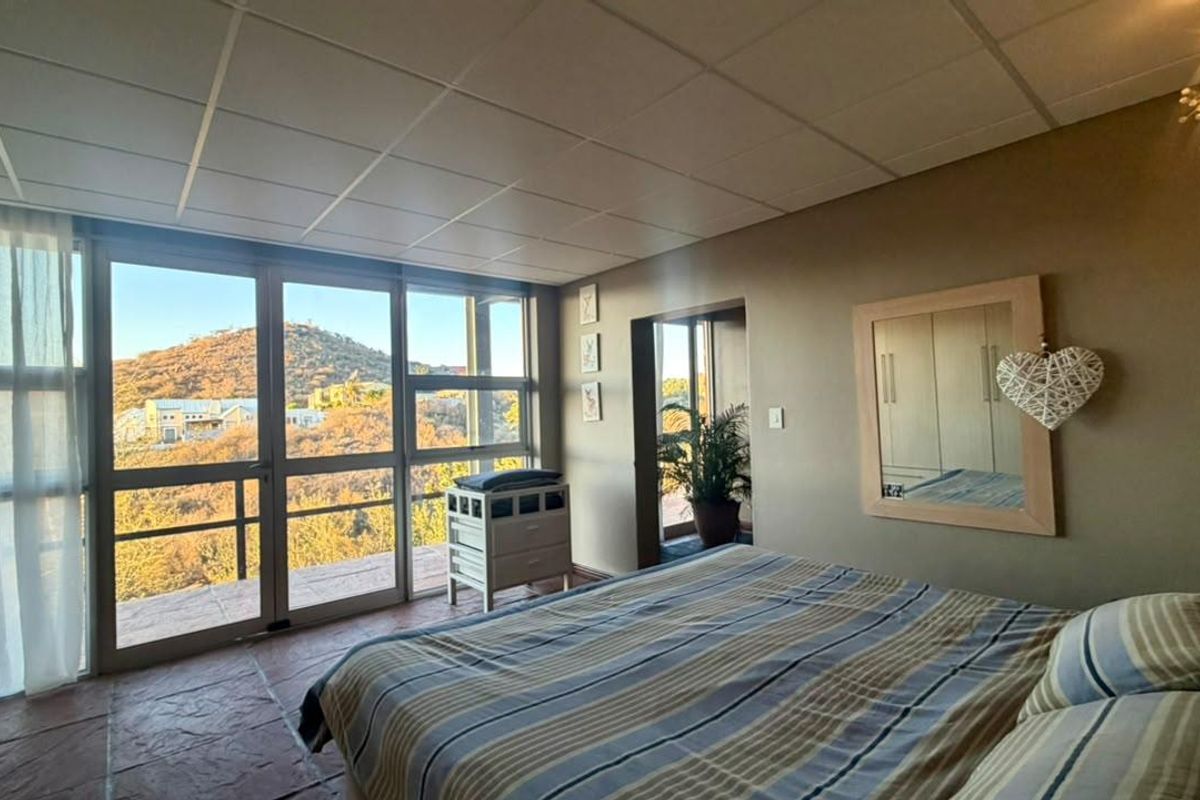 Spacious bedroom featuring large glass sliding doors that provide natural light and scenic hillside views, complemented by tiled flooring and built-in storage.