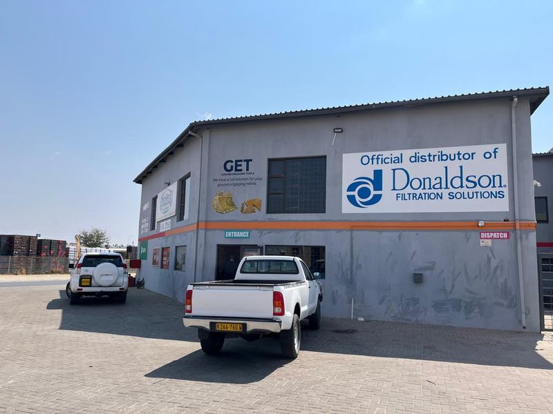 Front exterior view of a commercial industrial building featuring paved parking, clear signage, and designated entrance and dispatch access points.