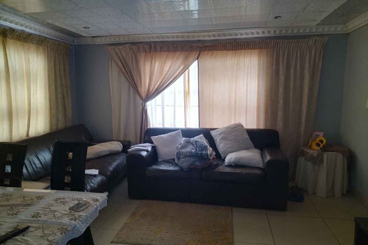 A living room area featuring tiled flooring and a drop ceiling, providing a functional space for relaxation.