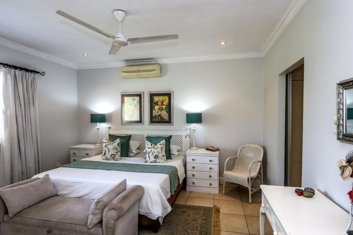 A well-maintained bedroom featuring tiled flooring, a ceiling fan, and a wall-mounted air conditioning unit.