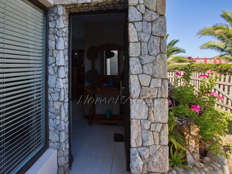 Entrance area featuring natural stone cladding, tiled flooring, and a large window with venetian blinds, providing access to the interior.