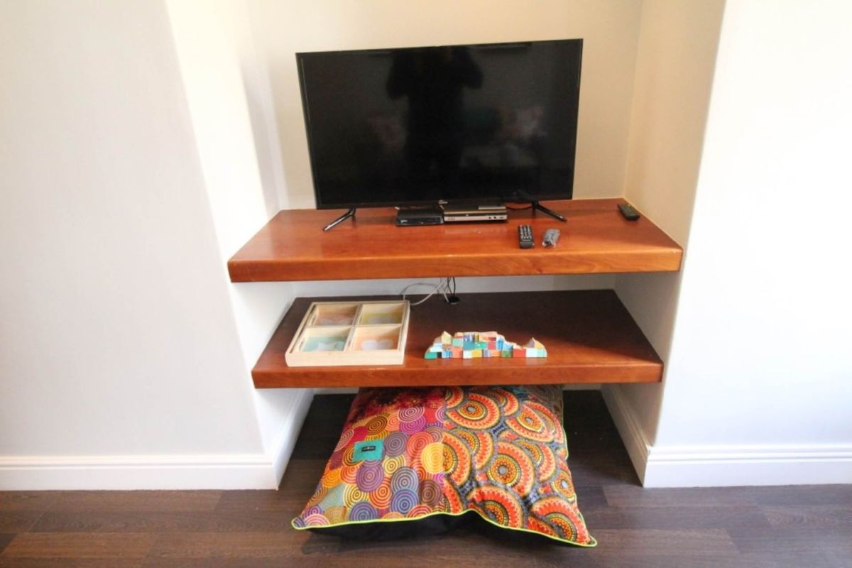 A recessed alcove featuring custom-fitted wooden shelving units, providing a functional storage solution within the living area.