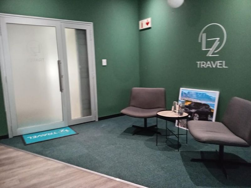 A professional office reception area featuring green accent walls, carpeted flooring, and a frosted glass entrance door.