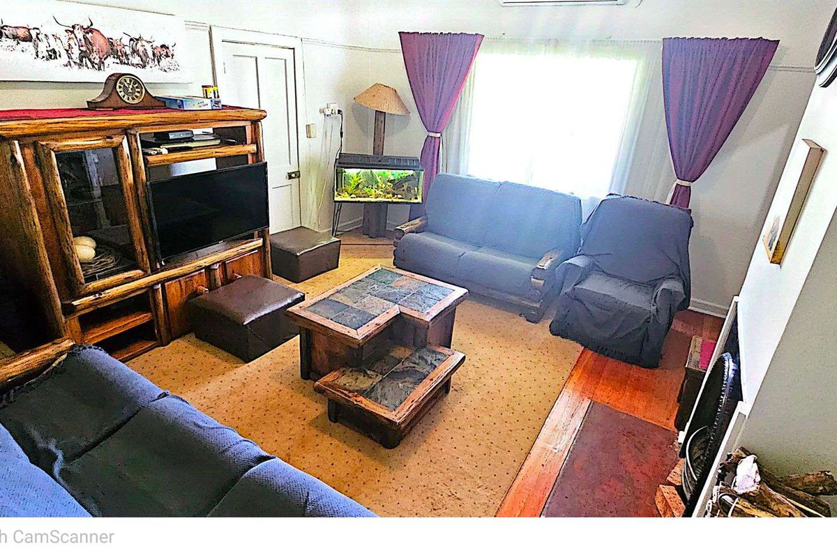 A cozy living room featuring a fireplace hearth, wooden flooring, and a large window allowing natural light into the space.