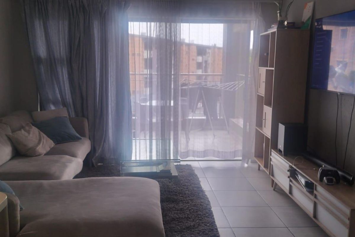 A living room featuring tiled flooring and a large sliding glass door providing access to an outdoor balcony area.