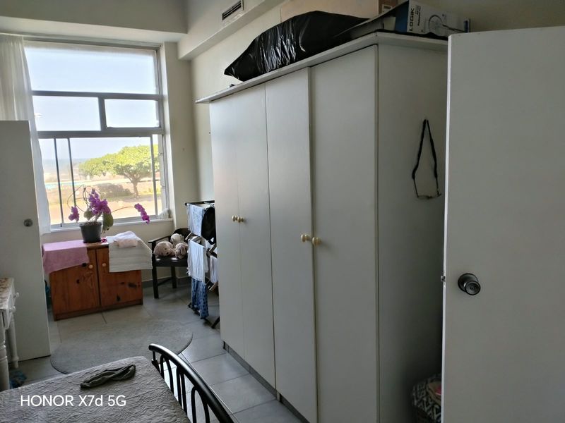 A bedroom featuring a large window with natural light, tiled flooring, and a built-in wardrobe.