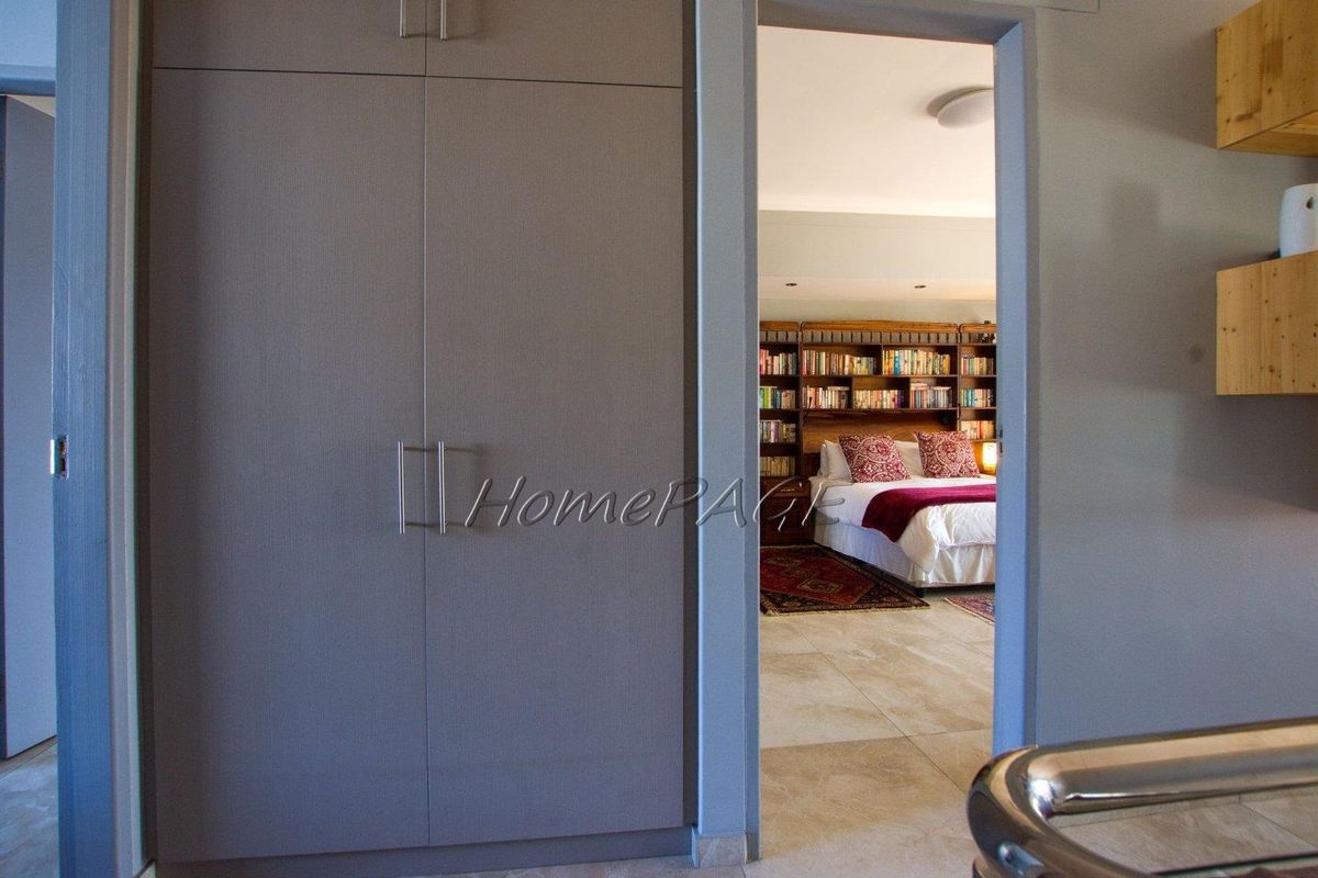 A view through a doorway into a bedroom featuring built-in cupboards, tiled flooring, and recessed lighting.