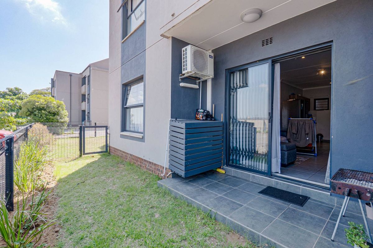 Ground floor apartment featuring a tiled patio area, private garden space, and wall-mounted air conditioning unit with direct access to the interior living area.