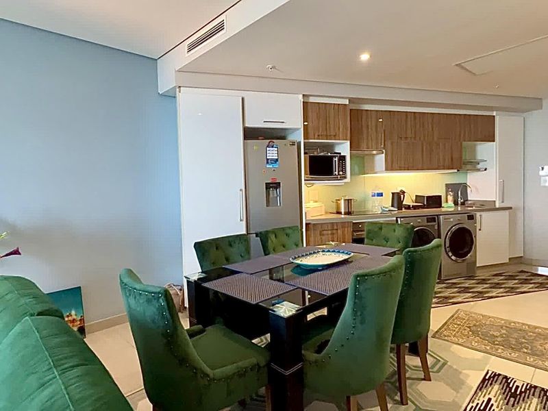 Modern open-plan living and kitchen area featuring sleek cabinetry, integrated appliances, and recessed lighting in a well-maintained apartment setting.