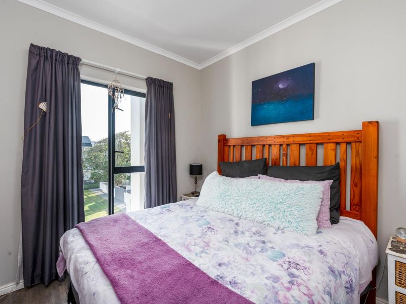 A well-maintained bedroom featuring laminate flooring, neutral wall finishes, and a sliding glass door providing natural light and access to the exterior.