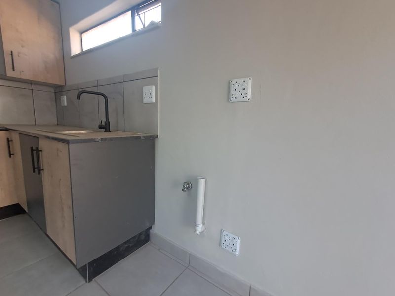 A functional laundry area featuring built-in cabinetry, a sink with a modern faucet, and dedicated plumbing and electrical connections for appliances.