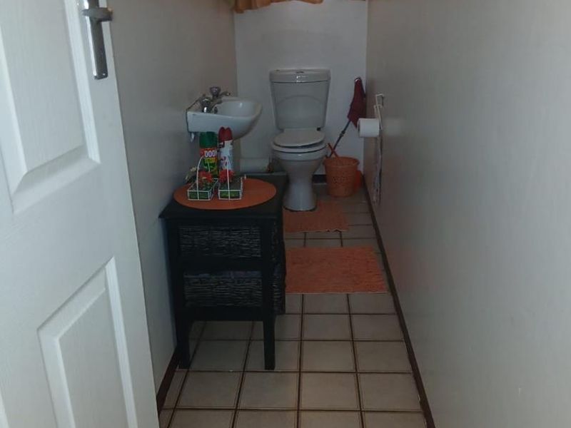 A compact bathroom featuring ceramic floor tiles, a wall-mounted basin, and a standard toilet.