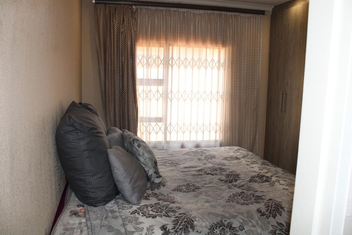 A bedroom featuring built-in cupboards and a window fitted with a security gate.