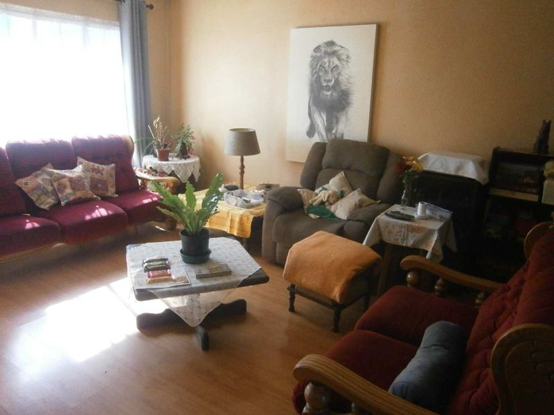 A living room featuring laminate flooring and natural light from a large window, providing a comfortable and functional space.