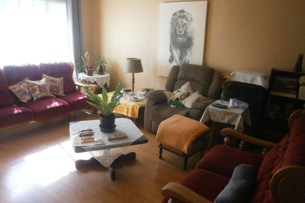 A living room featuring laminate flooring and natural light from a large window, providing a comfortable and functional space.
