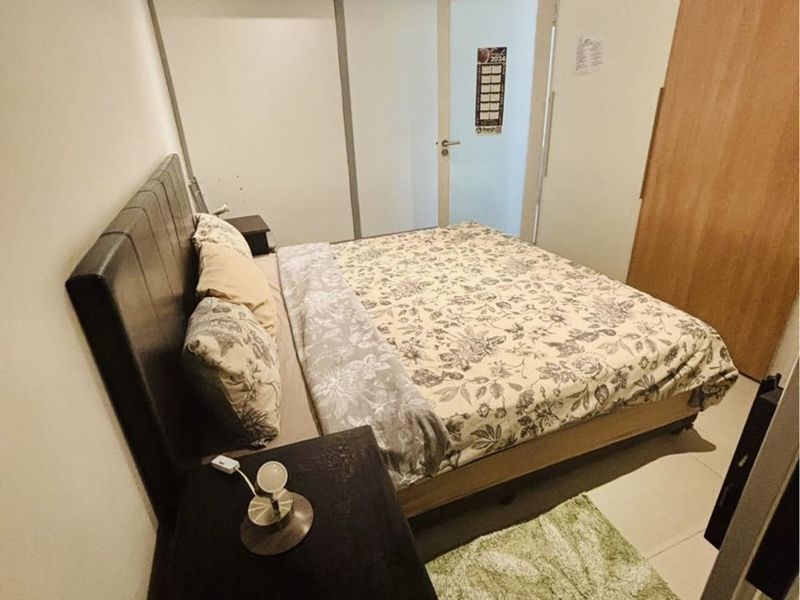 A functional bedroom featuring a built-in wardrobe, air conditioning unit, and a transom window above the door for added natural light.