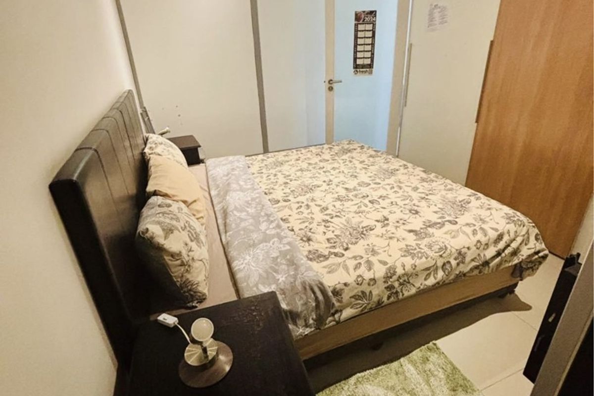 A functional bedroom featuring a built-in wardrobe, air conditioning unit, and a transom window above the door for added natural light.