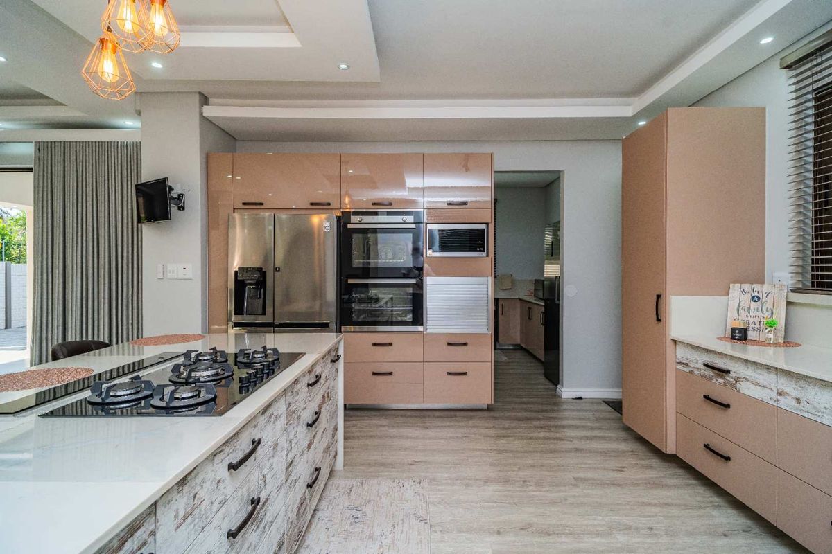 Modern kitchen featuring a central island with a gas cooktop, integrated wall ovens, built-in microwave, and sleek cabinetry with stone countertops.