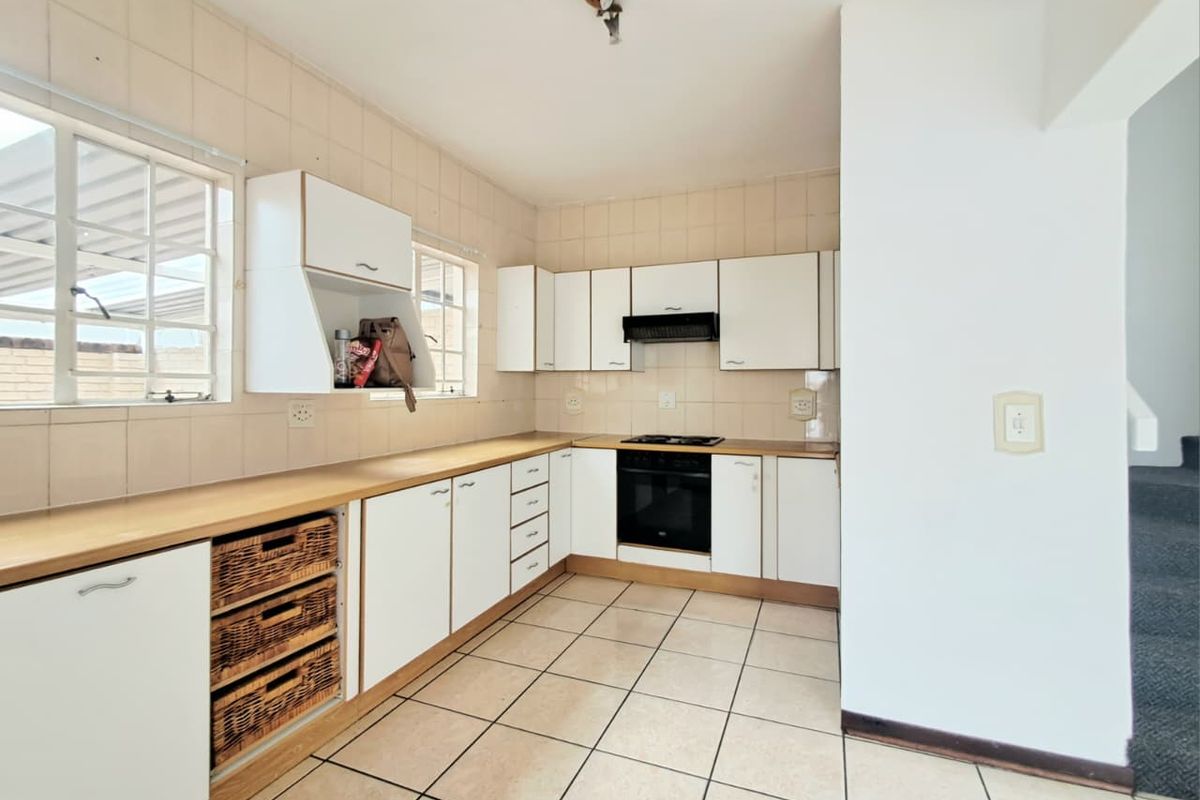 A functional kitchen featuring white built-in cabinetry, tiled splashbacks, a built-in oven with hob, and tiled flooring.