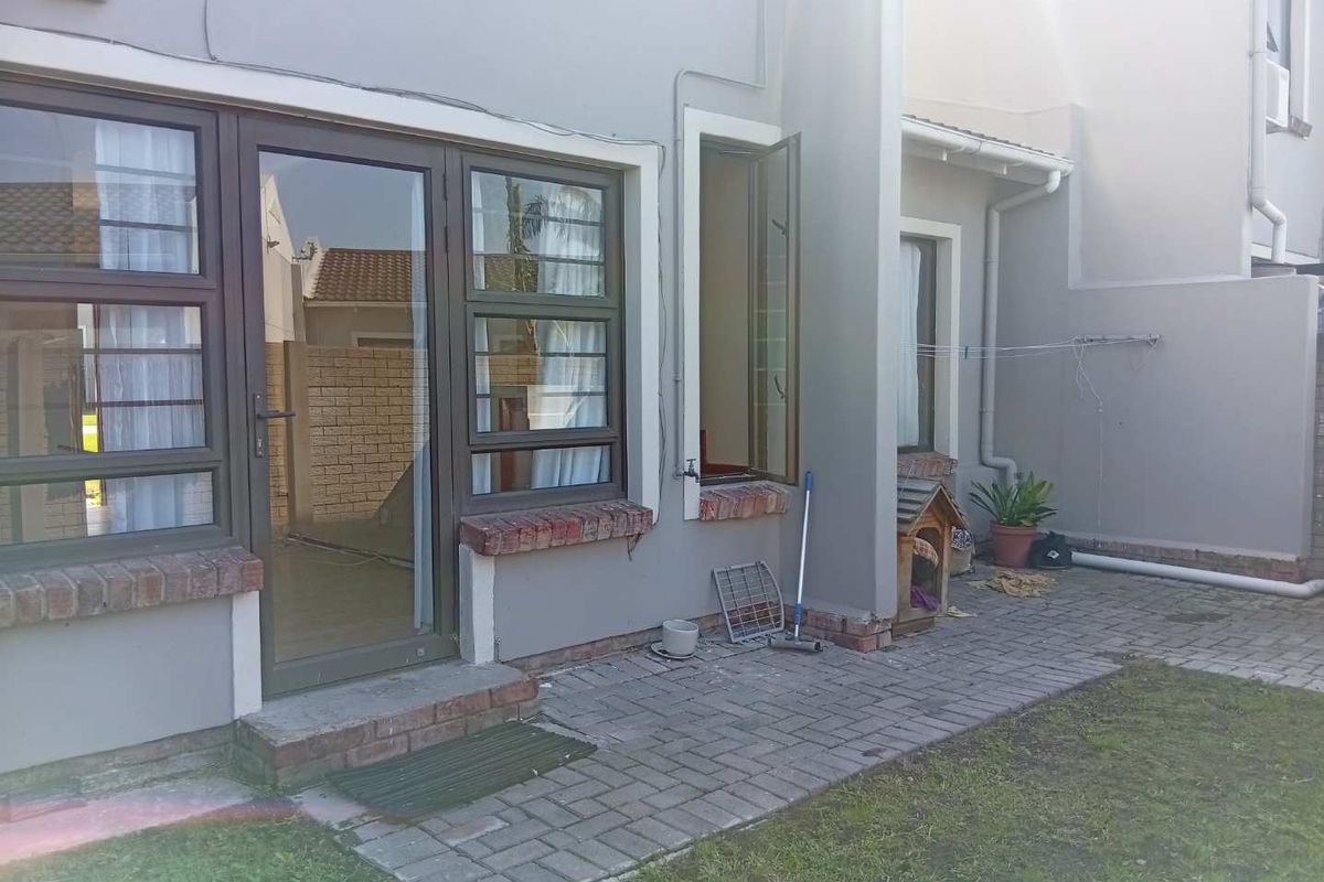Rear exterior view of the townhouse featuring a paved patio area, aluminium framed windows, and brick detailing.
