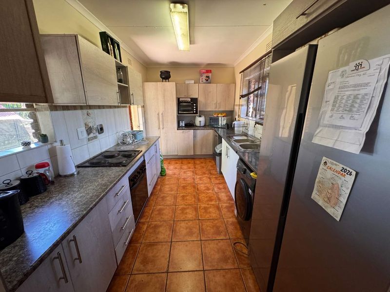A functional kitchen featuring built-in cabinetry, laminate countertops, an electric hob, oven, and tiled flooring with a practical layout.