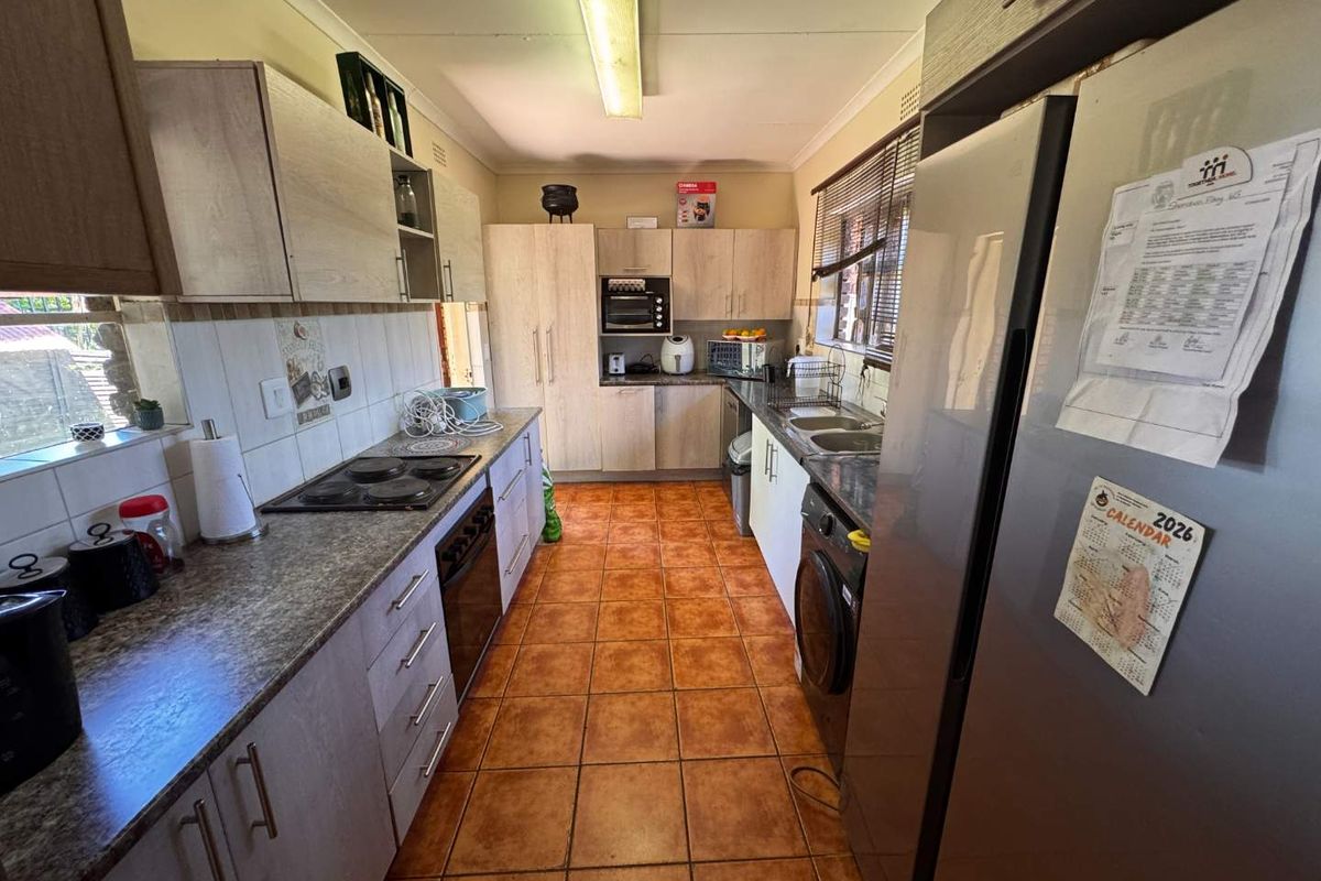 A functional kitchen featuring built-in cabinetry, laminate countertops, an electric hob, oven, and tiled flooring with a practical layout.