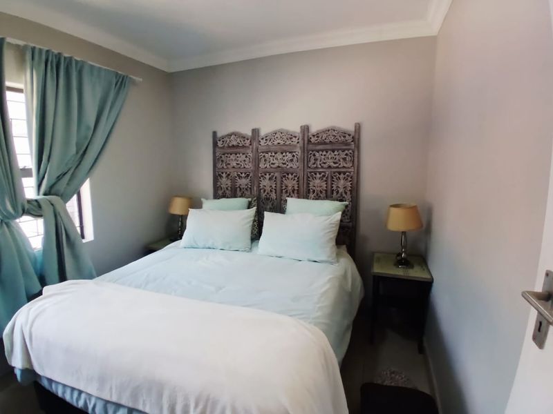 A cozy bedroom featuring neutral wall tones, coving, and a window fitted with security bars, providing a comfortable and functional sleeping space.