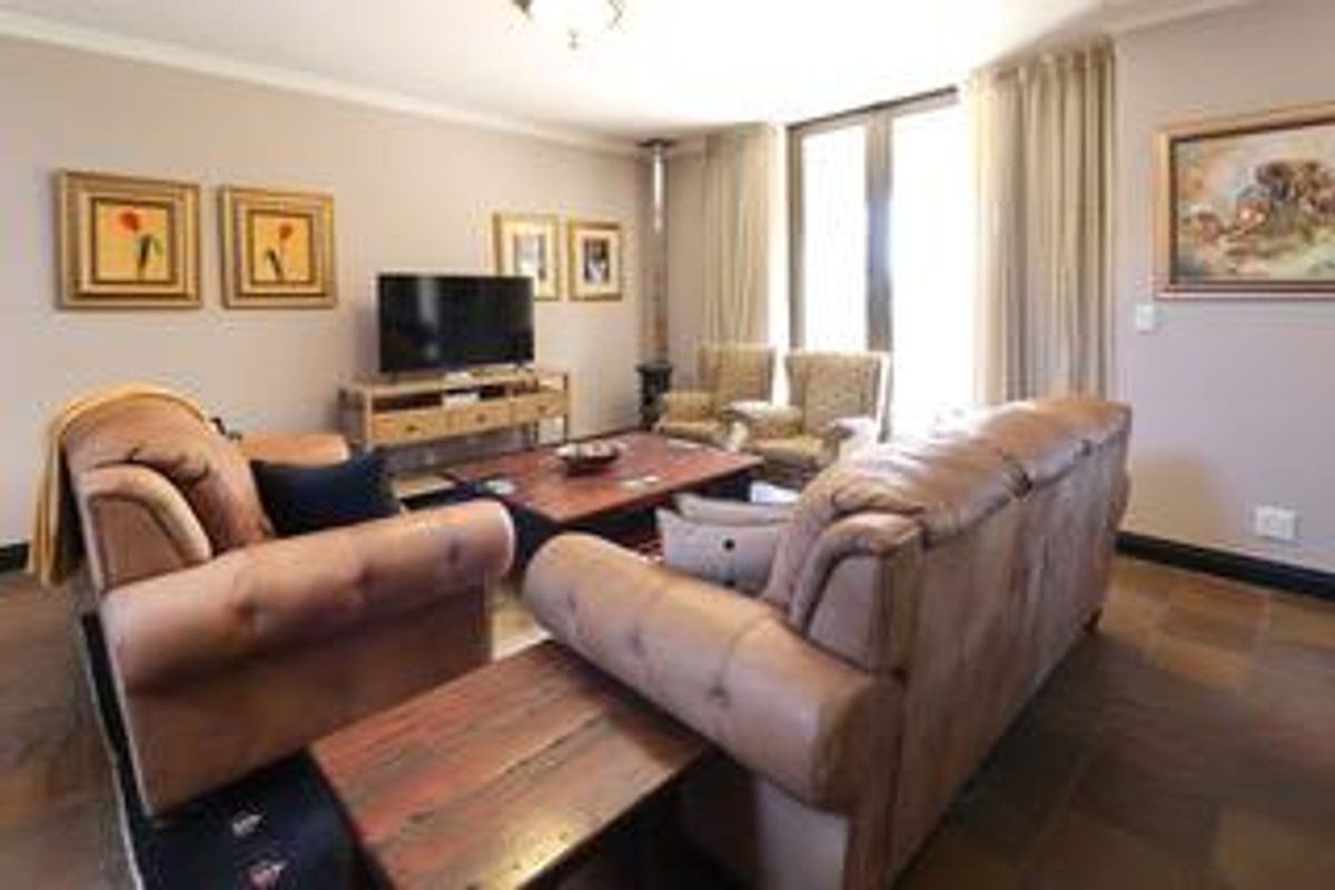 A comfortable living room featuring tiled flooring, large windows with curtains, and a built-in fireplace, providing a warm and inviting atmosphere.