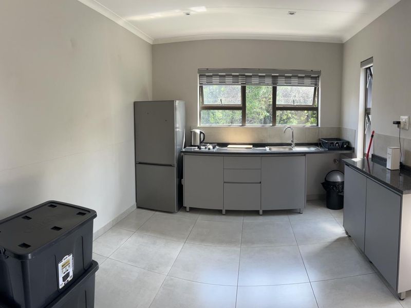A functional kitchen featuring modern grey cabinetry, granite countertops, tiled flooring, and a large window providing natural light.