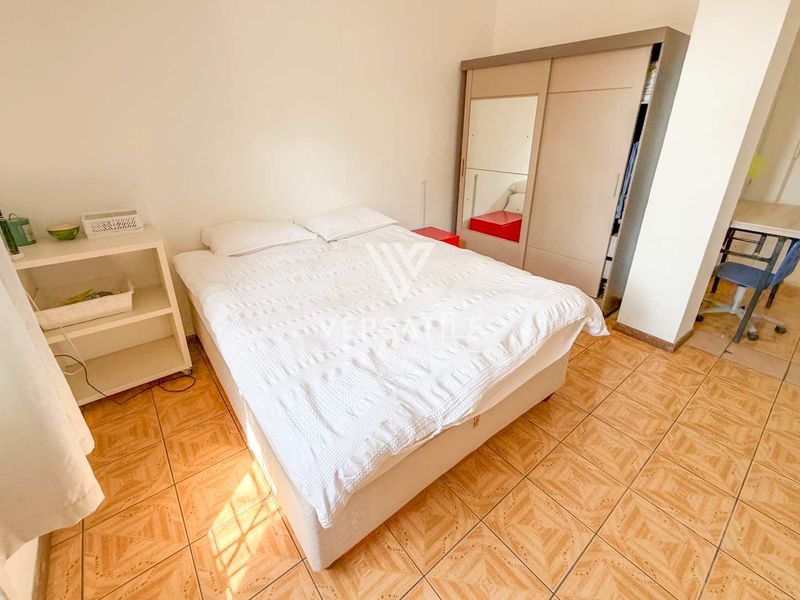 A bedroom featuring tiled flooring and a built-in wardrobe with a mirrored panel.