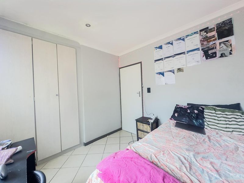 A functional bedroom featuring tiled flooring, built-in wardrobe storage, and recessed ceiling lighting.