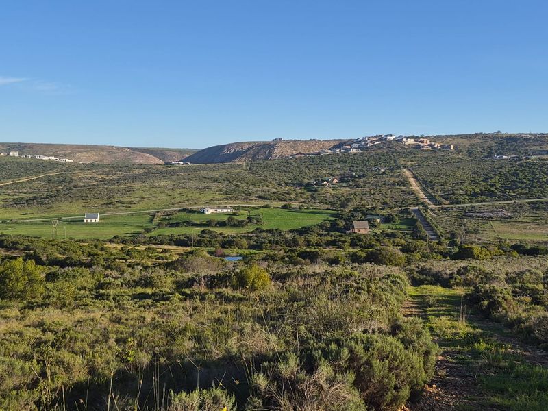 A wide-angle view of the expansive rural landscape and surrounding natural terrain, showcasing the open space and distant hillside development.