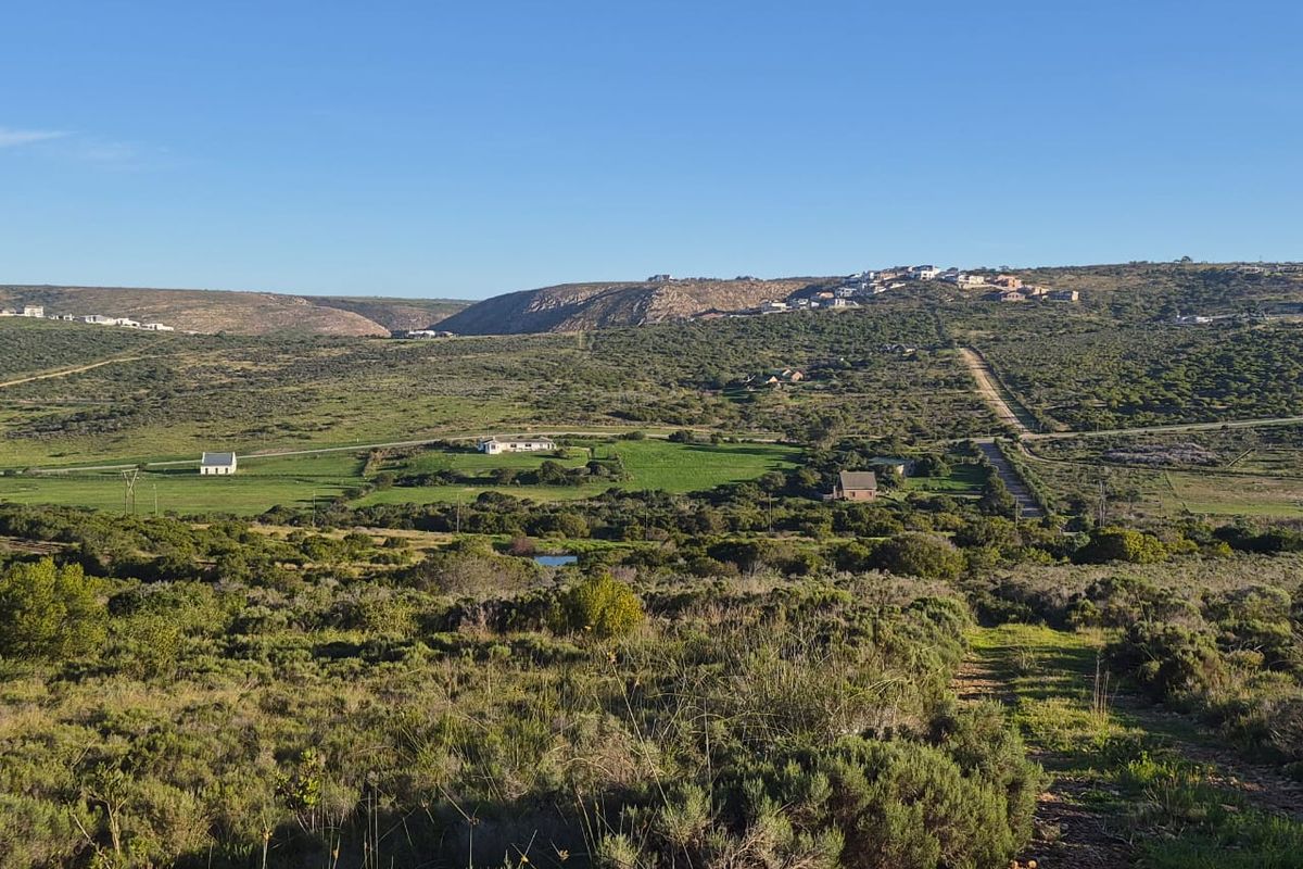 A wide-angle view of the expansive rural landscape and surrounding natural terrain, showcasing the open space and distant hillside development.