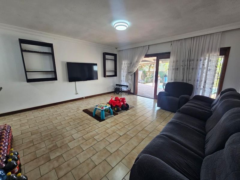 Spacious living room featuring ceramic tile flooring, built-in wall shelving, and large sliding glass doors providing direct access to the outdoor patio area.