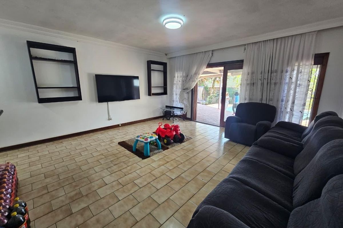 Spacious living room featuring ceramic tile flooring, built-in wall shelving, and large sliding glass doors providing direct access to the outdoor patio area.