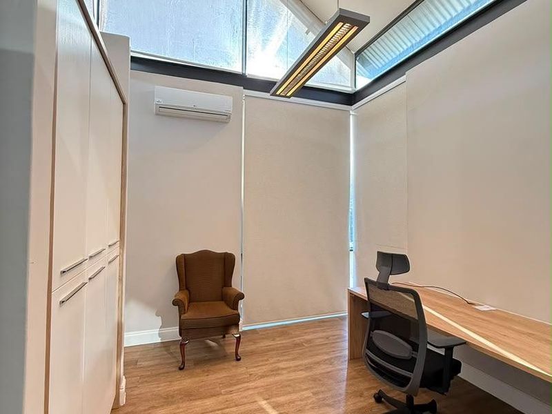 Modern office space featuring high ceilings with clerestory windows, built-in cabinetry, a custom desk, and split-system air conditioning.