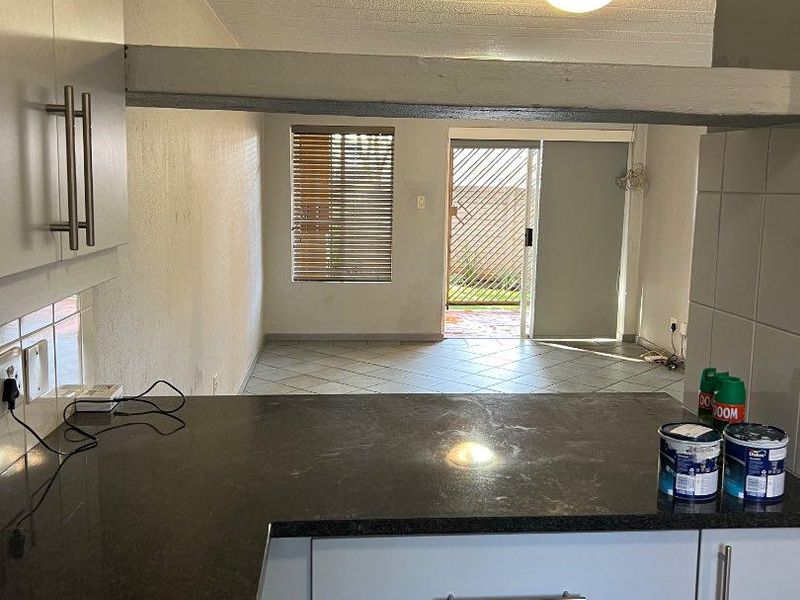 Open plan kitchen and living area featuring granite countertops, tiled flooring, and direct access to an outdoor patio space.